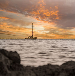 Sailboat on sea against sky during sunset