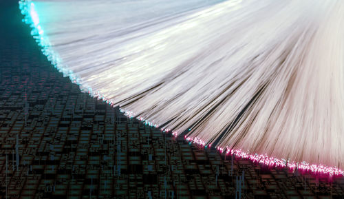 Illuminated fanned out optical fiber closeup in abstract technical back