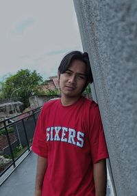 Portrait of young woman standing against building