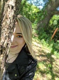 Portrait of young woman against tree trunk