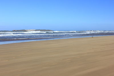 Scenic view of beach against clear blue sky