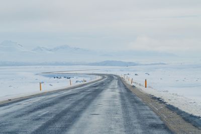 Road leading towards snowcapped mountains against sky