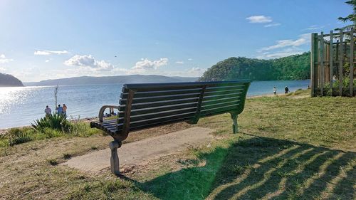 Bench on beach by sea against sky