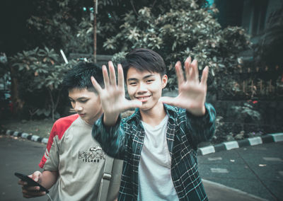 Portrait of man gesturing while standing with male friend on road