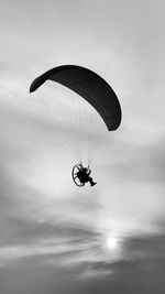 Low angle view of person paragliding against sky