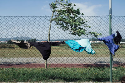 Clothes hanging on chainlink fence against sky