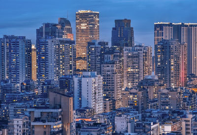 Illuminated buildings in city against sky at dusk