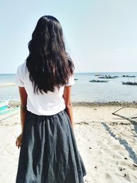 Rear view of young woman looking at sea against clear sky