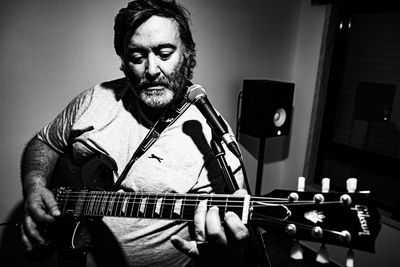 Portrait of man playing guitar at home