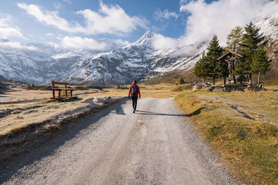 Woman walking on footpath amidst fall colored highland and snow capped mountains in gastein, austria