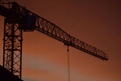 Low angle view of crane boom against sky during sunset