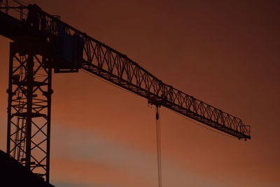 Low angle view of electricity pylon against sky during sunset