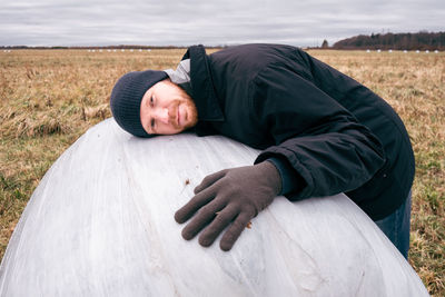 Portrait of farmer lying on haystack