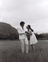 Rear view of couple on field against sky