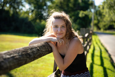 Portrait of smiling young woman standing against trees