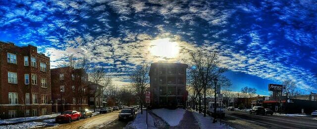 Cars on road in city against cloudy sky