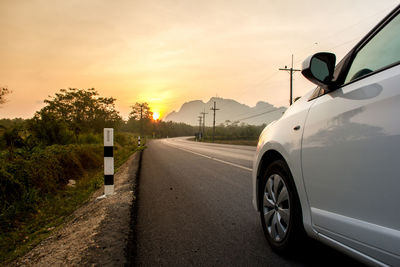 Car on street against sky during sunset