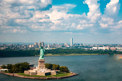 Statue of buildings in city against cloudy sky