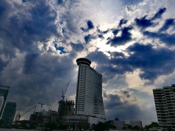 Low angle view of skyscrapers against cloudy sky