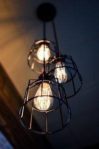 Low angle view of illuminated light bulb hanging from ceiling