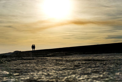 Silhouette man standing on sand dune in desert