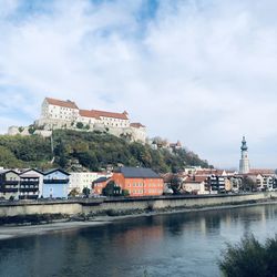 Buildings by river against sky in city