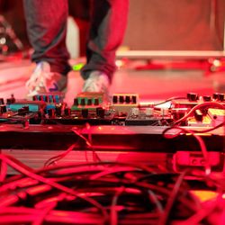 Low section of man standing by sound mixer at nightclub