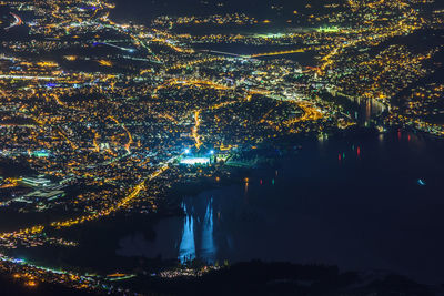 Aerial view of illuminated cityscape by river at night