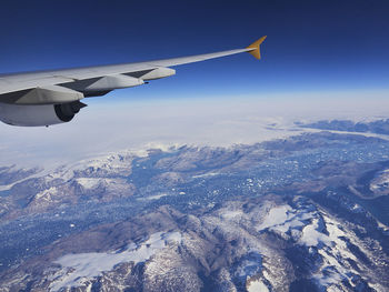 Aerial view of aircraft wing over mountains against sky