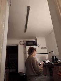 Side view of woman sitting at home