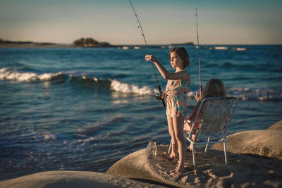 Sisters fishing at riverbank in summer