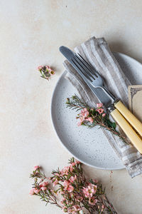 Romantic or spring table setting. knife and fork, little pink flowers and linen napkin on a plate