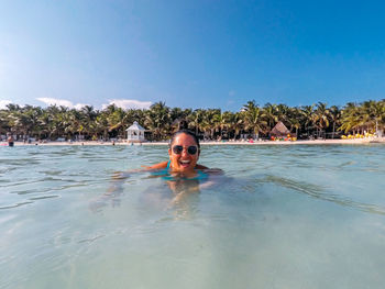 Portrait of happy young woman swimming in sea against sky