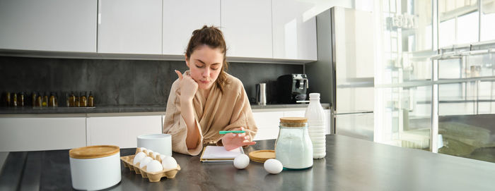 Side view of young woman using mobile phone at home