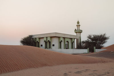 Mosque in desert against clear sky