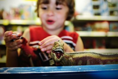 Toy dinosaur against boy in shop