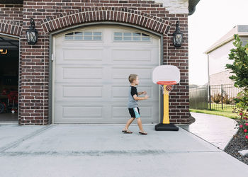 Happy boy playing basketball on driveway