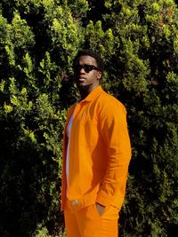 Young man wearing sunglasses standing against trees