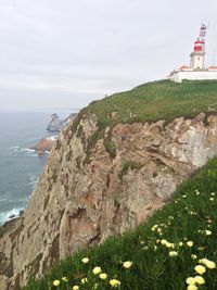 Scenic view of sea by cliff against sky