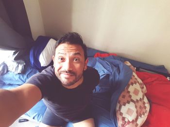 Portrait of man sitting on bed at home