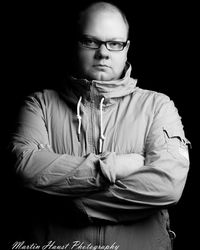 Portrait of man sitting against black background