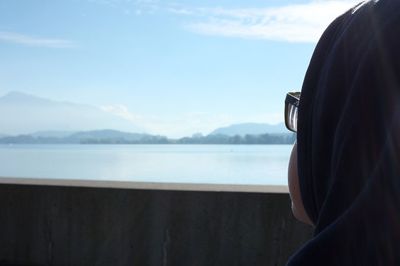 Rear view close-up of woman looking at lake zug against sky