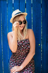 Portrait of smiling young woman standing against blue wall