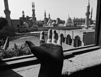 Cropped image of hand on temple against building