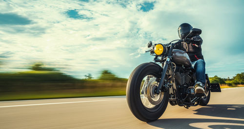 Man riding motorcycle on road against sky