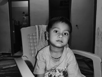 Portrait of boy sitting on table at home