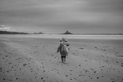 Rear view of girl walking on sand at beach