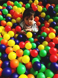 High angle view of cute baby boy sitting amidst multi colored balls