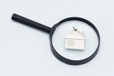High angle view of magnifying glass with model home on white background
