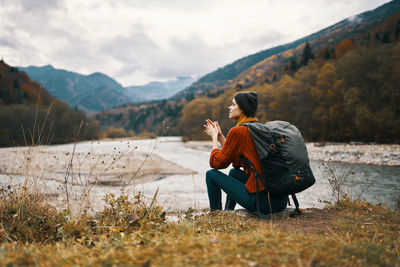 Rear view of couple sitting on mountain against sky